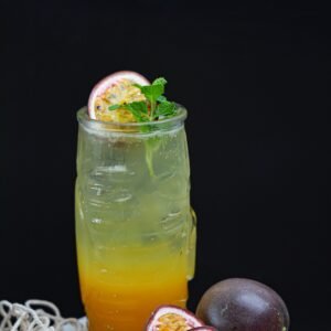 A vibrant passion fruit and citrus drink garnished with fresh mint leaves, perfect for a summer refreshment.