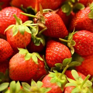 Pile of fresh red strawberries with green leaves, perfect for food photography.