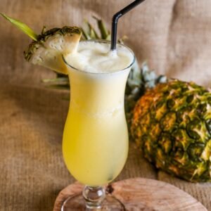 Chilled pineapple juice in a glass with a straw and sliced pineapple garnish.